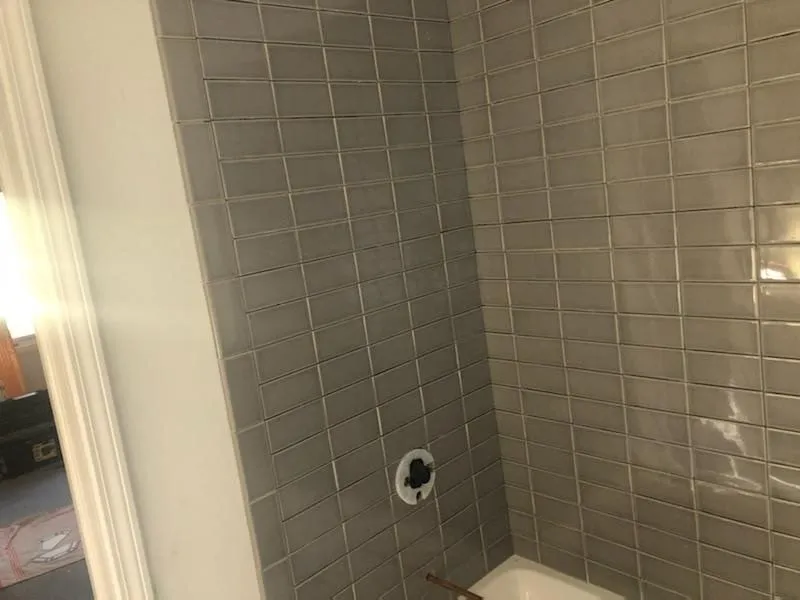 Glossy gray subway tile installation wrapping around a bathroom corner